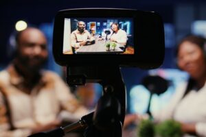 Focus on vlogging camera used by cohosts in blurry background streaming podcast during live debate