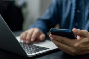 Man hand holding mobile smartphone digital technology network communications at desk.